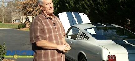 En man står bredvid en Mustang. (AI text)
