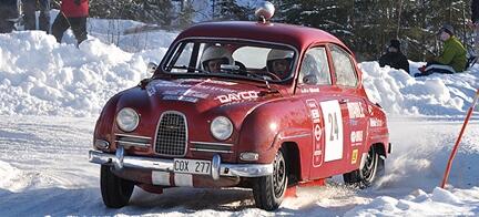 En klassisk bil kör nerför en snöig väg. (AI text)