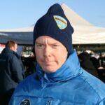 En man i en blå jacka står framför en snöig äng. (AI text)