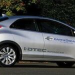 En silverfärgad Honda Civic Hybrid parkerad vid gatan. (AI text)