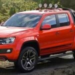 En röd Volkswagen Amarok lastbil parkerad i en skog. (AI text)