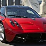 En röd sportbil kör nerför en gata. (AI text)