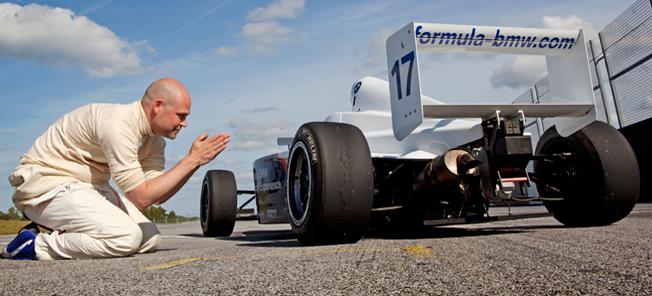 en man på knä bredvid en racebil (AI text)