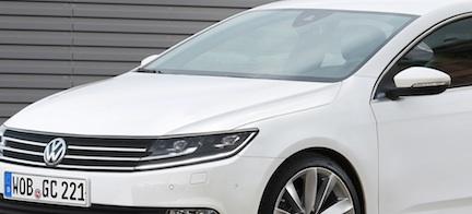 En vit Volkswagen Passat parkerad framför en garageport. (AI text)