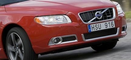 En röd Volvo S60 kör nerför en landsväg. (AI text)