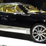 En svart och guld bil på utställning vid en bilmesse. (AI text)