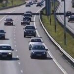 En bil kör nerför en motorväg. (AI text)