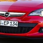 En Opel Astra - en röd bil kör nedför en väg. (AI text)