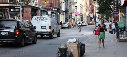 En stadsgata med bilar och folk. (AI text)