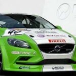 En grön Volvo V40 RS TDI parkerad framför ett byggnad. (AI text)