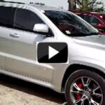 En Jeep Grand Cherokee parkerad framför en garage. (AI text)
