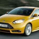 En gul Ford Focus ST kör nerför en väg. (AI text)