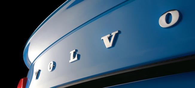 Volvo-logotypen på förgrillskenet av en blå bil. (AI text)