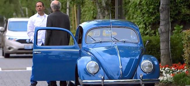 En man och kvinna står bredvid en blå Volkswagen Käfer. (AI text)