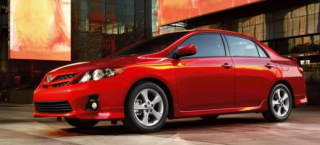 En röd Toyota Corolla parkerad framför ett byggnad. (AI text)