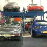 En garage med flera bilar i det. (AI text)