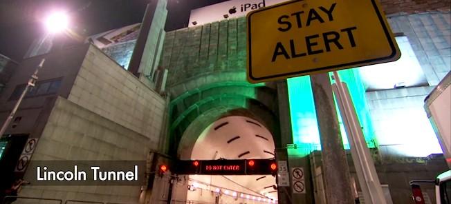 En skylt varnar folk om att vara uppmärksamma i Lincoln-tunneln. (AI text)