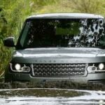 En Land Rover Defender kör genom en smutsig, blöt område. (AI text)