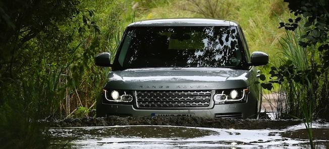 En Land Rover Defender kör genom en smutsig, blöt område. (AI text)