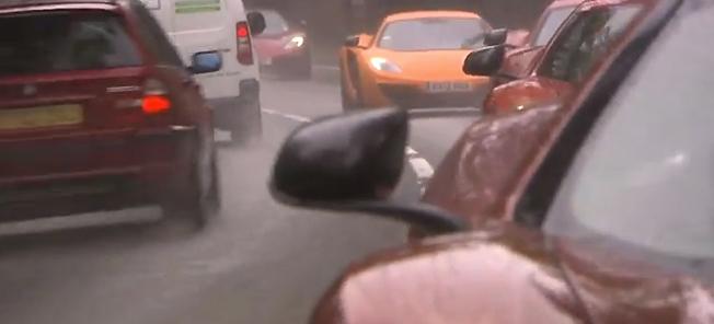 En bil kör nedför en väg i regnet. (AI text)