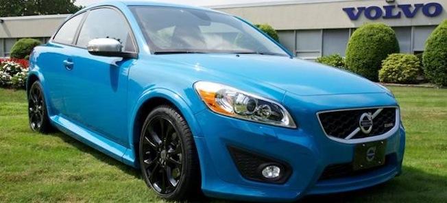 En blå Volvo S60 parkerad framför en Volvo-handlare. (AI text)