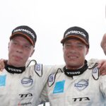 Bilsportförare ställer upp med händerna i luften. (AI text)