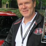 En man står bredvid en bil. (AI text)