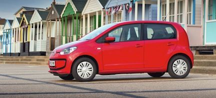 En röd Volkswagen up! parkerad framför en strandvilla. (AI text)