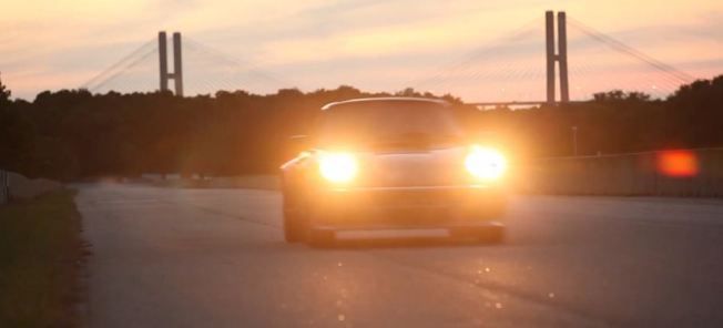 En bil kör nerför en väg vid solnedgången. (AI text)