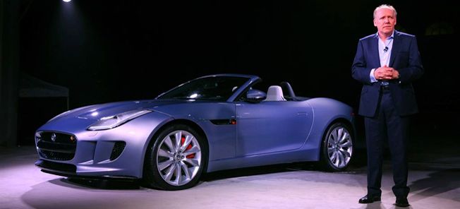 En man i kostym står bredvid en Jaguar F-Type. (AI text)