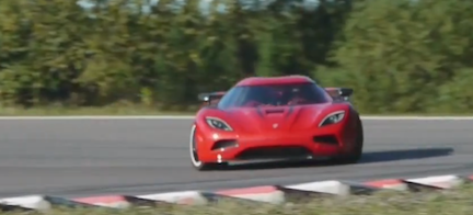 En röd sportbil kör på en bana. (AI text)