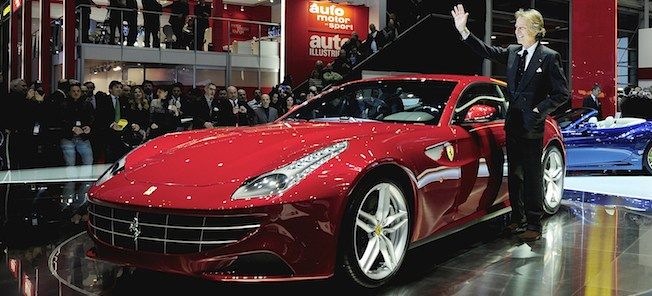 En man står bredvid en röd sportbil på bilsalongen. (AI text)