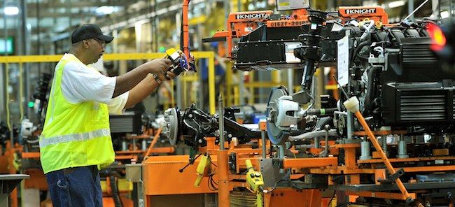 En arbetare arbetar på en bilmotor i en fabrik. (AI text)