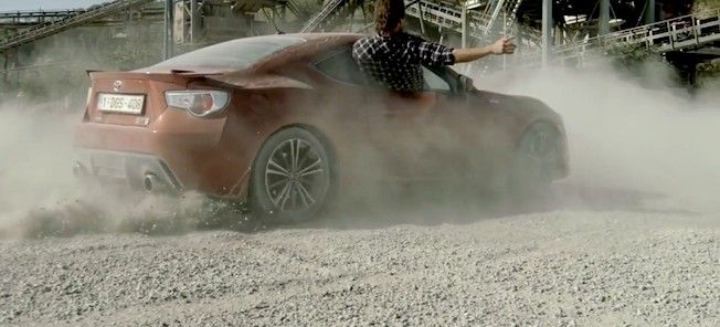 En röd sportbil kör på en grusväg. (AI text)