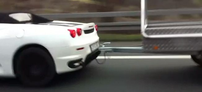 En vit sportbil som dras bakom ett släp. (AI text)