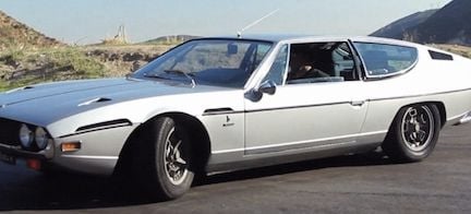 En klassisk bil parkerad vid vägkanten. (AI text)