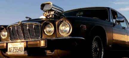 En klassisk bil står parkerad i en åker. (AI text)