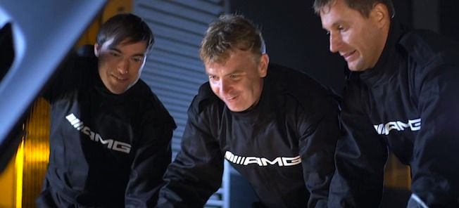 En grupp män i svarta jackor arbetar med en bil. (AI text)