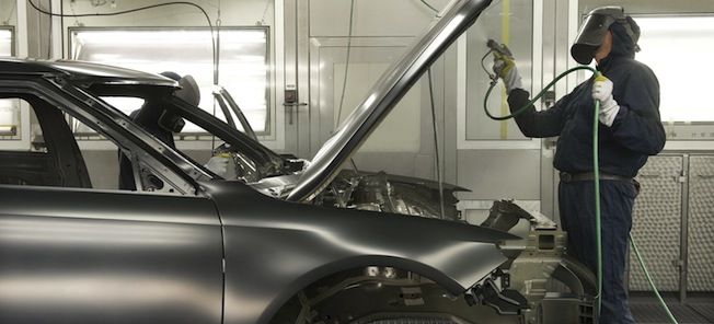 En man svetsar en bil i en garage. (AI text)