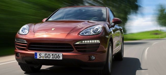 En röd Porsche Cayenne kör nerför en landsväg. (AI text)