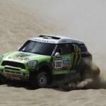 En gröngul Mini Cooper glider nedför en sanddyne. (AI text)