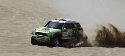 En gröngul Mini Cooper glider nedför en sanddyne. (AI text)