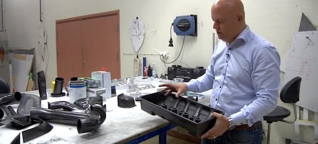 En man arbetar med en bil i en verkstad. (AI text)