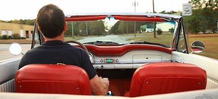 En man kör en klassisk bil i en roadster. (AI text)