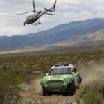 En helikopter flyger över en rallybil. (AI text)