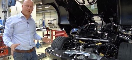 En man står bredvid en bil i en garagelänga. (AI text)