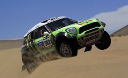 En grönt Mini Cooper S svävar över en sanddyne. (AI text)