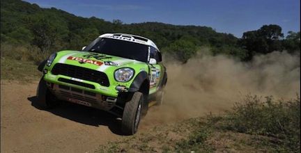 En grön Mini Cooper S kör nedför en grusväg. (AI text)