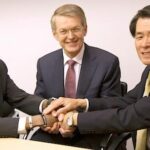 En grupp män i kostym och slips sitter vid en bord. (AI text)