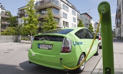 En grön bil parkerad vid en el-laddstation. (AI text)